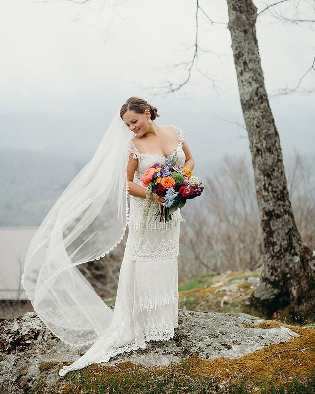 Bride in Kristene wedding dress wedding veil blowing in breeze.
