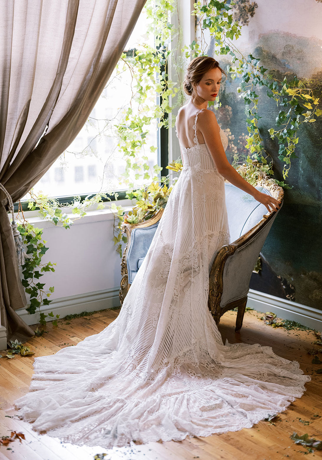 Side view of the Arbor wedding dress by Claire Pettibone, featuring intricate lace detailing, a fitted bodice, and a dramatic lace train in an ethereal bridal look.