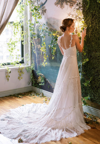 Claire Pettibone Arbor wedding gown showcasing the lace bodice, open back, and full-length skirt with floral lace and stripe details in a romantic, nature-inspired setting.