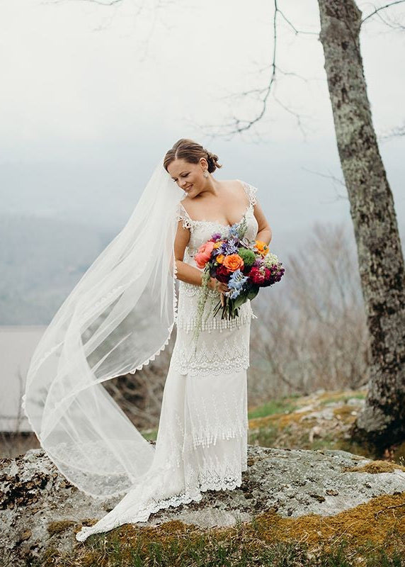 Bride in Kristene wedding dress wedding veil blowing in breeze.