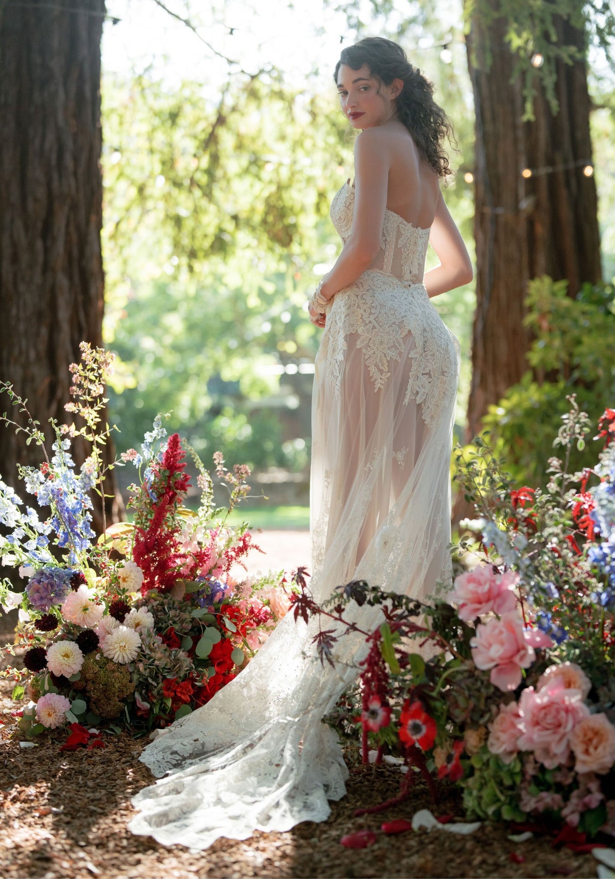 Back view of the Narcisse sheer chiffon wedding dress with floral embroidery among garden flowers