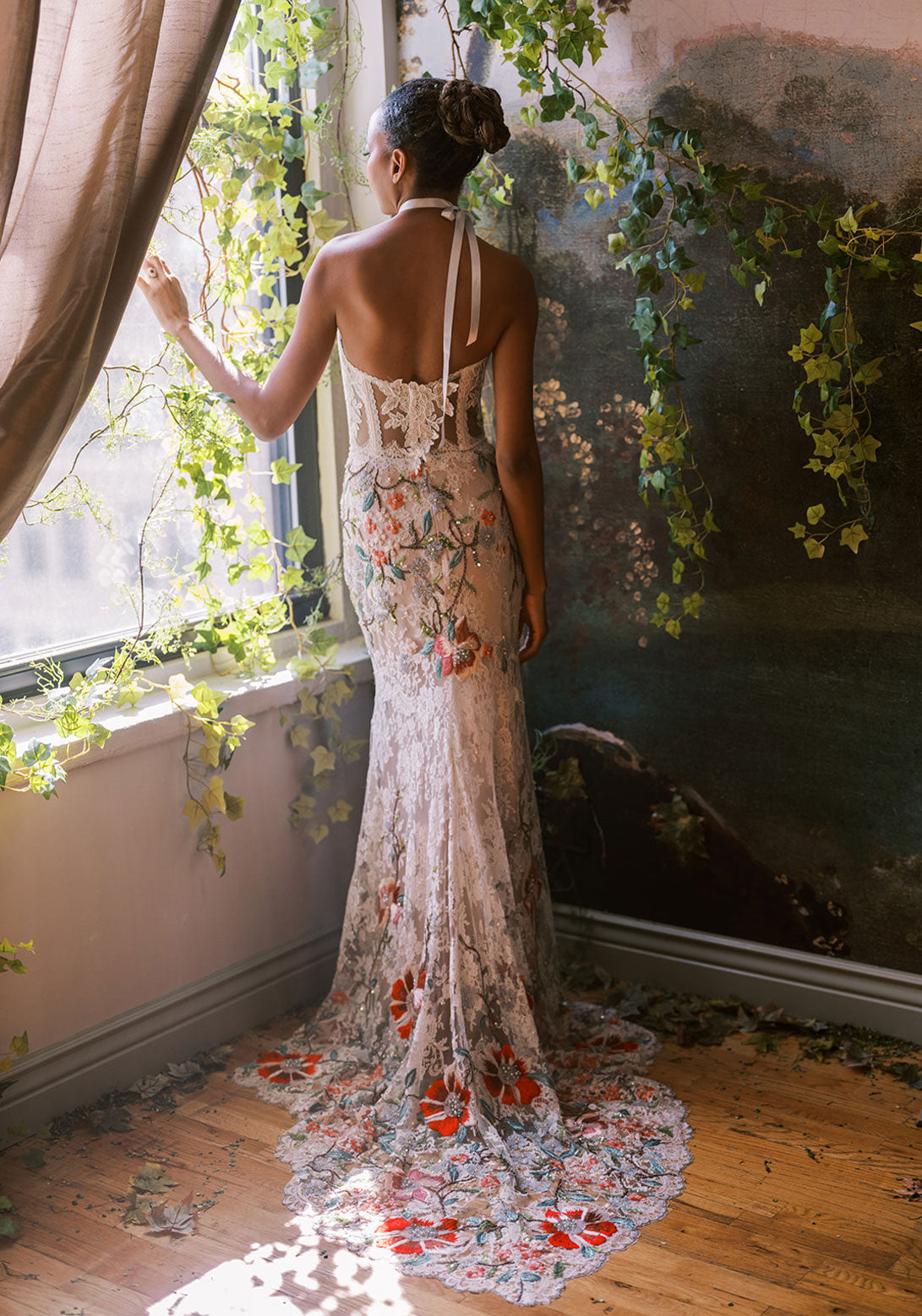 Back view of a luxury lace gown showcasing intricate floral embroidery and halter straps.