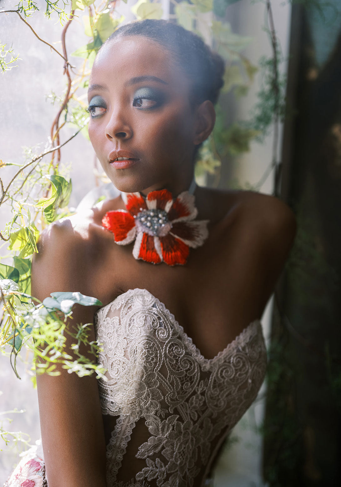 Close-up of the bride in an elegant embroidered lace gown, wearing a luxurious floral neckpiece.